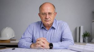 Ingeniero de caminos serio revisando planos de obra civil en oficina profesional